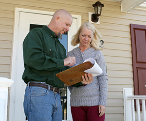 Insulation contractor showing information on a clipboard to a homeowner.