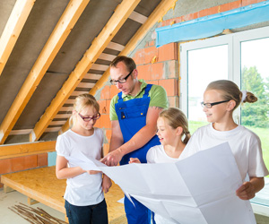 Worker in a blue apron showing plans to three girls.