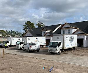 ABS Coastal company trucks parked outside of a new construction home.